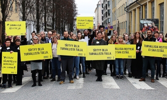 Ihmiset seisovat ryhmässä ja kantavat Amnestyn mielenosoituskylttejä.