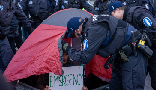 Poliisi kurkistaa punaiseen telttaan mielenosoituksessa.
