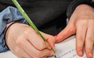 Oppilas kirjoittaa kynällä paperille.