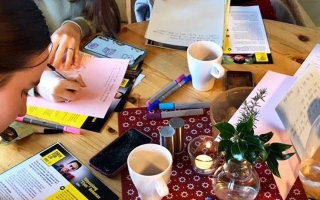 Nuoret kirjoittavat kirjeitä pöydän ääressä.