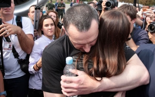 Kuvassa Oleg Sentsov halaa henkilöä median edustajien ympäröimänä.
