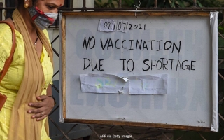 Ihminen pitää kättä vatsalla ja vieressä on kyltti, jossa lukee; "No vaccination due to shortage."
