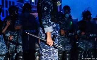 Kuvassa poliiseja, joista keskimmäinen pitää pamppua käsissään