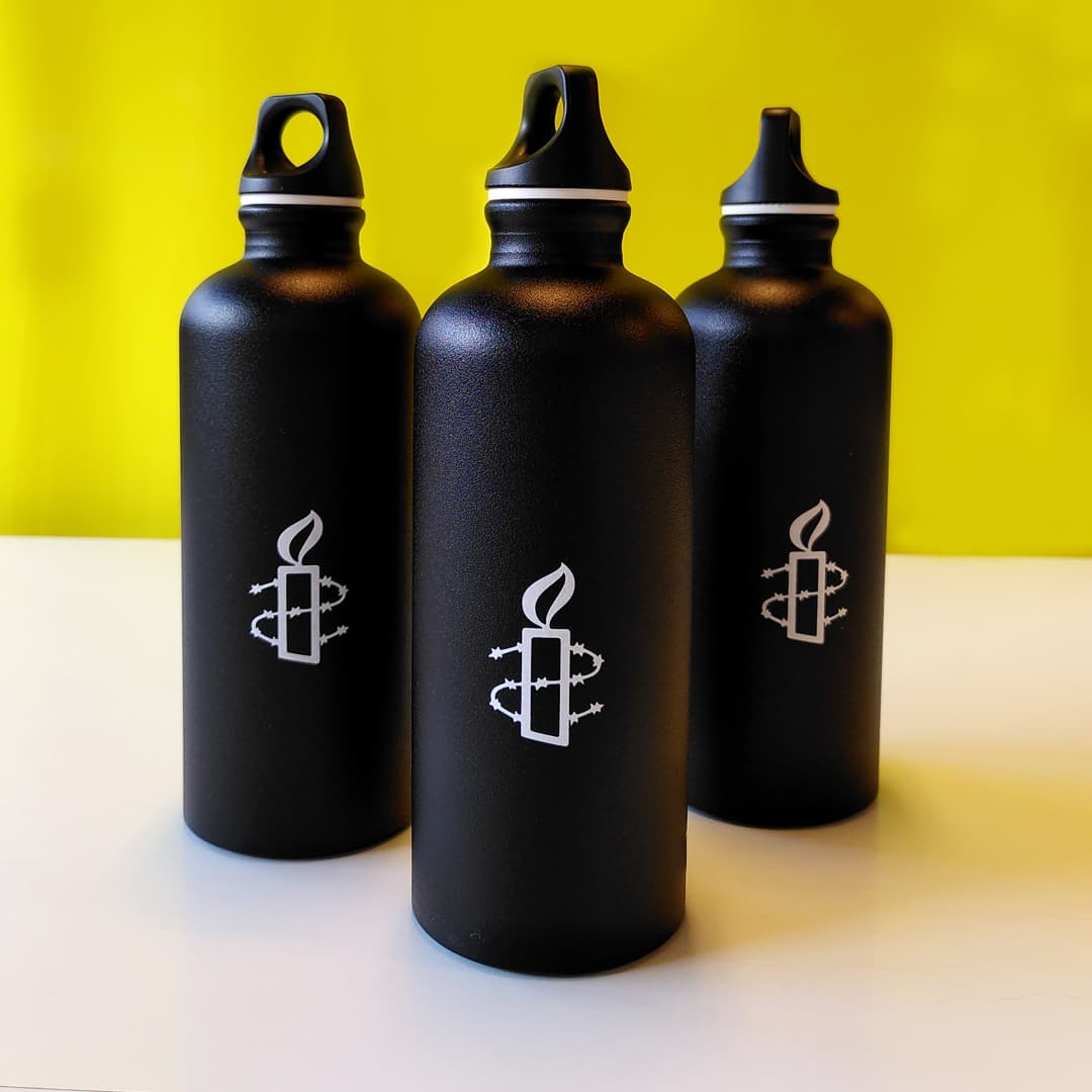Kolme mustaa juomapulloa, Amnestyn logo valkoisella