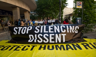 Mielenosoittajat pitävät yhdessä isoa banderollia, jossa lukee: "stop silencing diddent. Protect human rights."