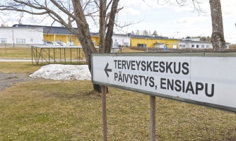 Maisema, jossa taustalla rakennus ja etualalla kyltti, jossa lukee "terveyskeskus, päivystys, ensiapu"