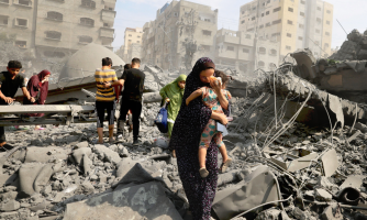 Ihmisiä tuhotun rakennuksen raunioissa Gazassa.
