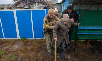 Iäkäs nainen, jota autetaan evakuoitumaan Ukrainassa.